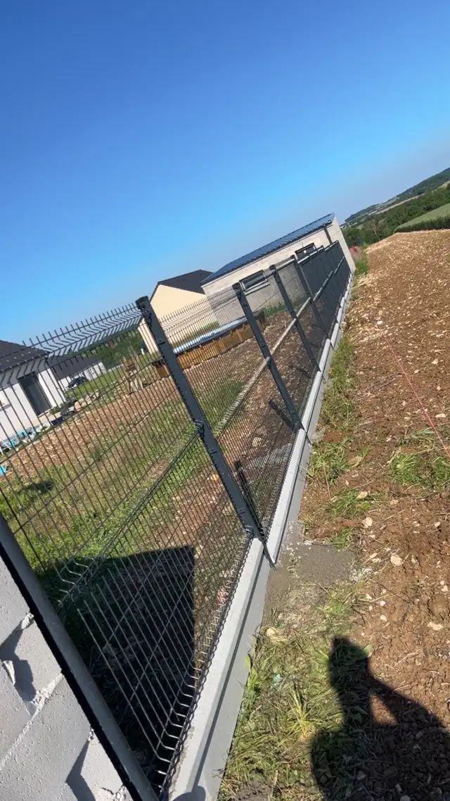Clôture rigide et portail en fer posés sur un muret maçonné