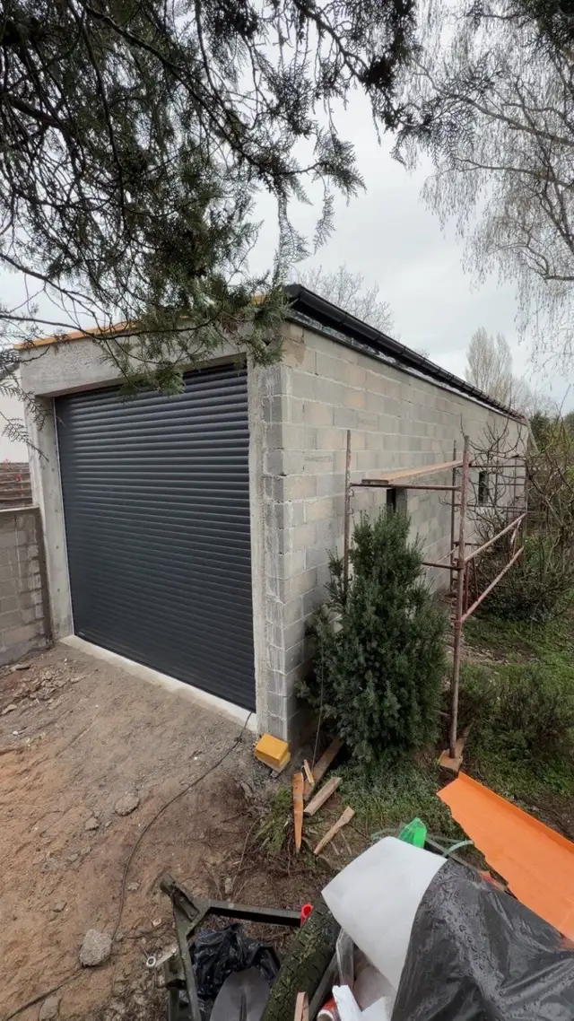 Garage en parpaings avec porte de garage posée, échafaudage en place