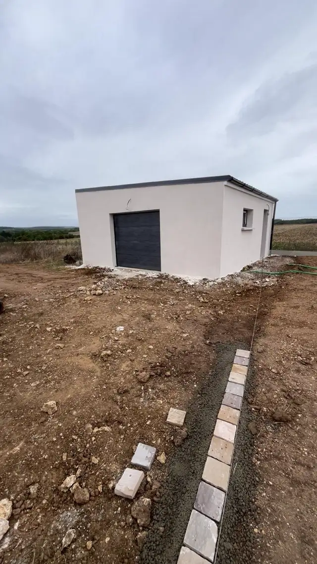 Garage maçonné enduit en blanc avec porte sectionnelle grise